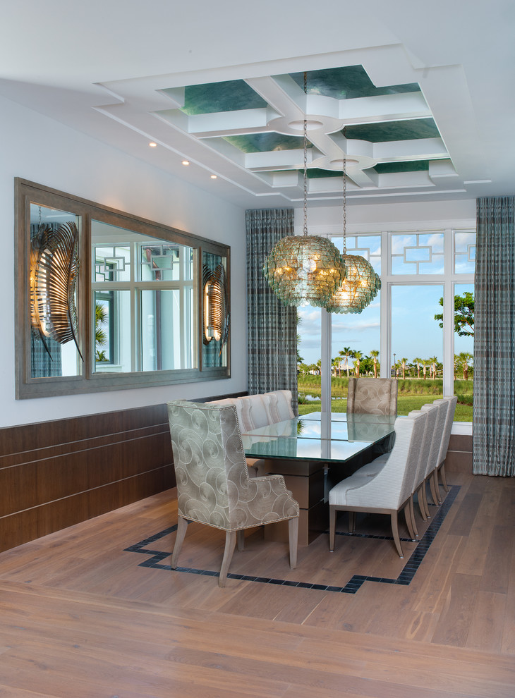 This is an example of a coastal dining room in Miami with white walls, light hardwood flooring and no fireplace.