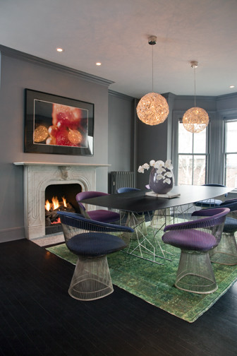Réalisation d'une salle à manger minimaliste avec un mur gris, parquet foncé, une cheminée standard, un manteau de cheminée en pierre et un sol marron.