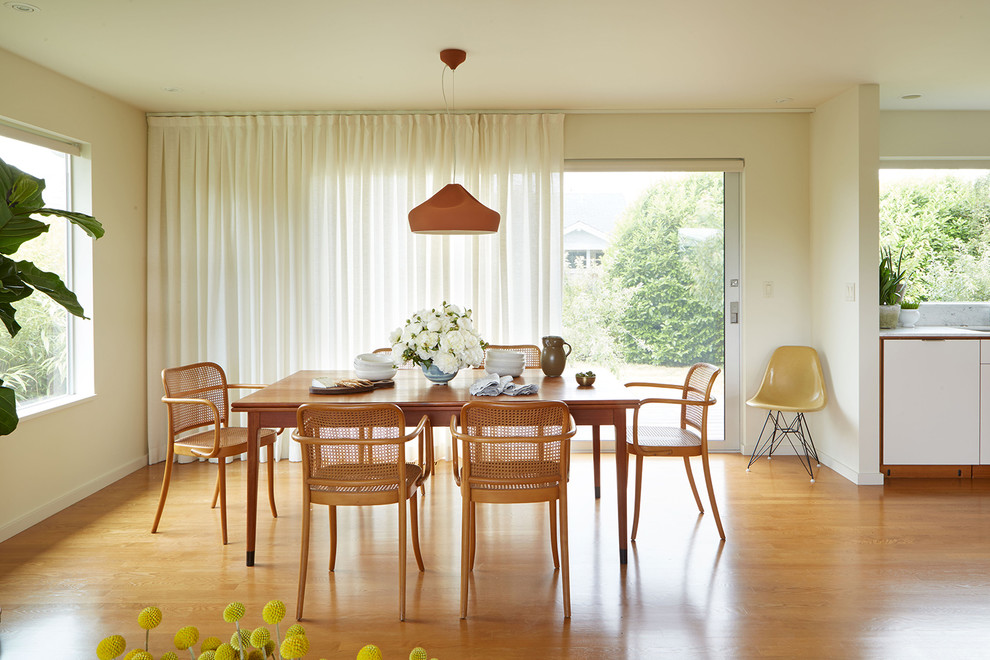 Immagine di una sala da pranzo aperta verso il soggiorno moderna con pareti bianche, pavimento in legno massello medio e pavimento arancione