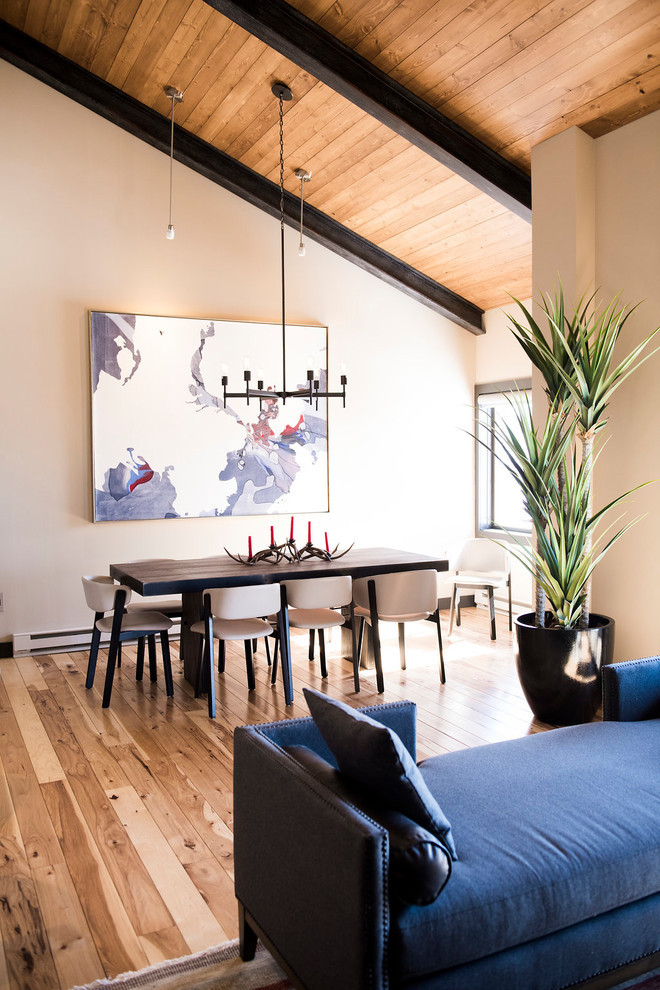 Cette image montre une salle à manger ouverte sur le salon design de taille moyenne avec un mur beige, un sol beige et un sol en bois brun.