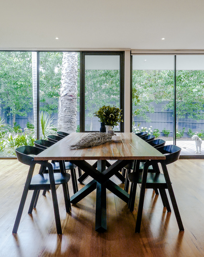 Immagine di una sala da pranzo aperta verso il soggiorno minimal con pavimento in legno massello medio e pavimento marrone