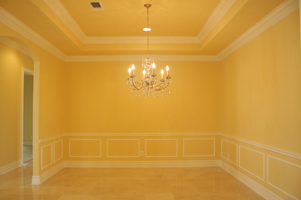 Geschlossenes, Großes Klassisches Esszimmer ohne Kamin mit gelber Wandfarbe und Porzellan-Bodenfliesen in Houston