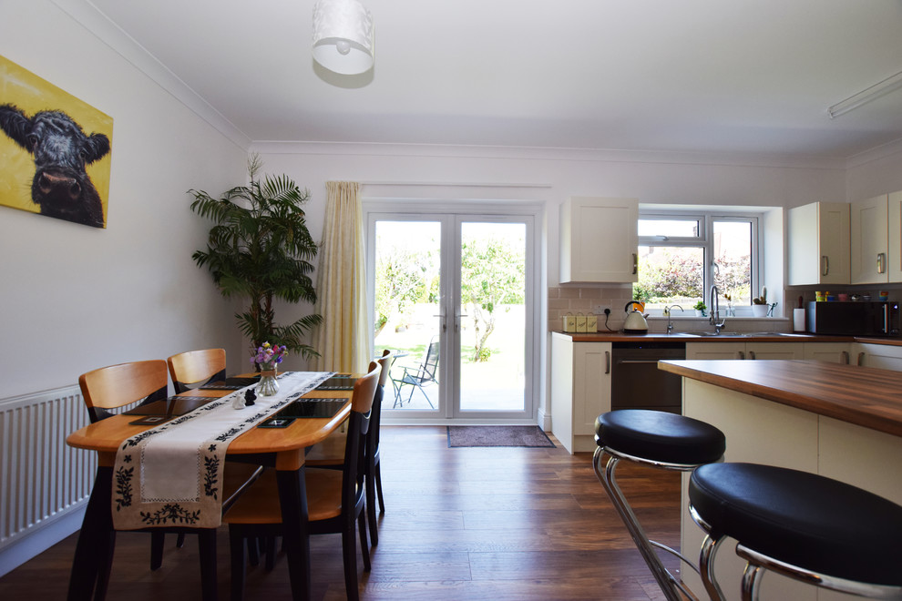Modelo de comedor de cocina clásico, grande, con paredes blancas, suelo laminado y suelo marrón