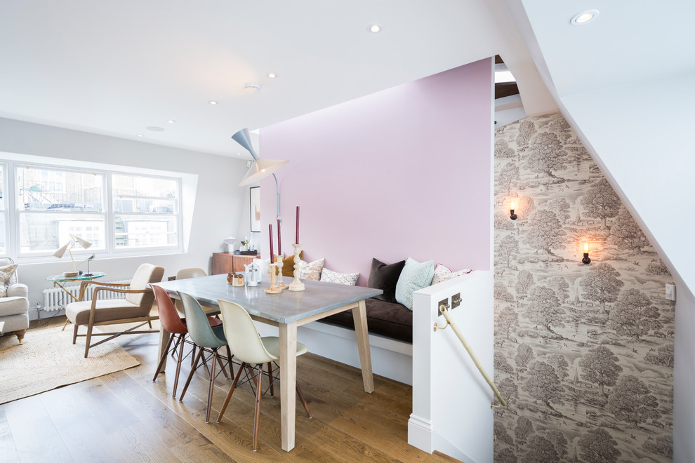 Cette photo montre une salle à manger ouverte sur le salon chic avec un mur rose et un sol en bois brun.