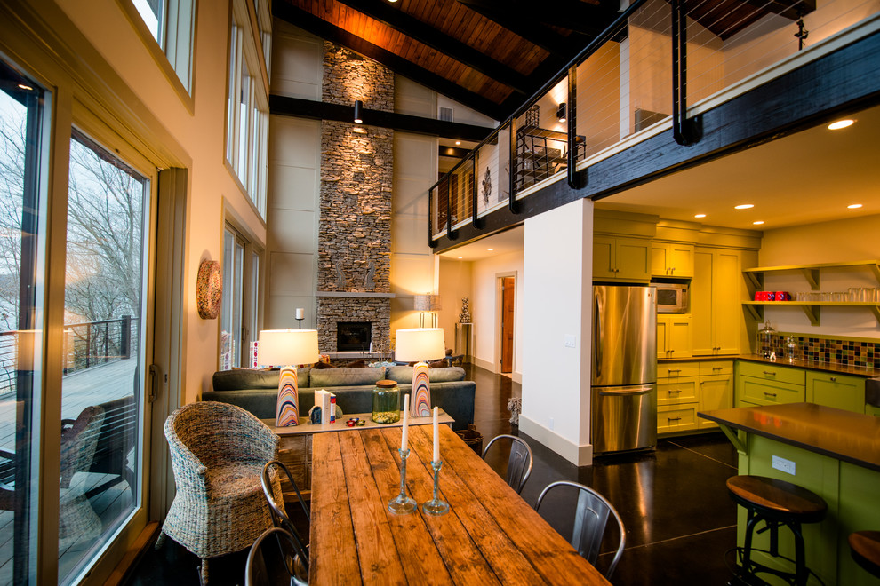 Aménagement d'une grande salle à manger ouverte sur le salon contemporaine avec un mur beige, sol en béton ciré, une cheminée standard, un manteau de cheminée en brique et un sol noir.