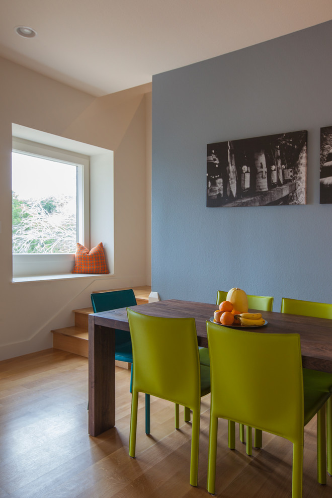 Idée de décoration pour une salle à manger ouverte sur la cuisine design de taille moyenne avec un mur bleu, un sol en bois brun et un sol beige.