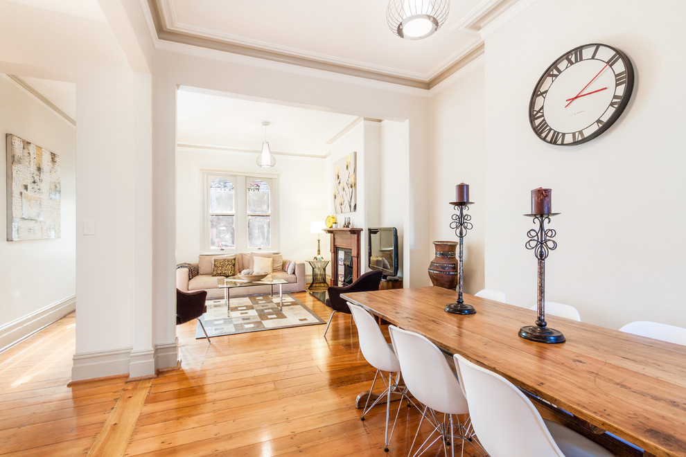 Cette image montre une salle à manger ouverte sur le salon design avec un mur beige et un sol en bois brun.