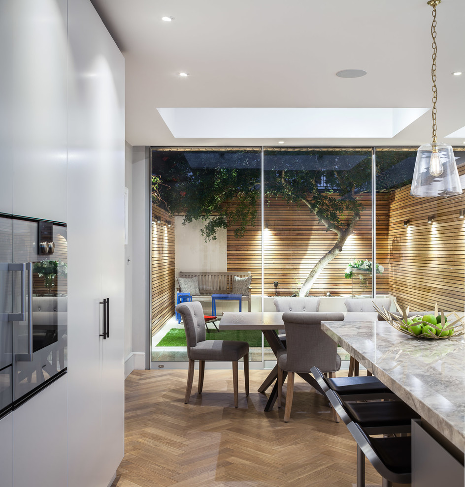 Exemple d'une salle à manger ouverte sur la cuisine tendance de taille moyenne avec un mur gris et parquet clair.