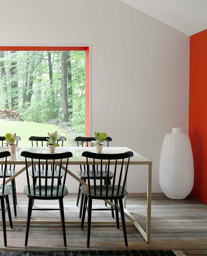 Foto di una sala da pranzo aperta verso la cucina minimalista di medie dimensioni con pareti rosse e parquet chiaro