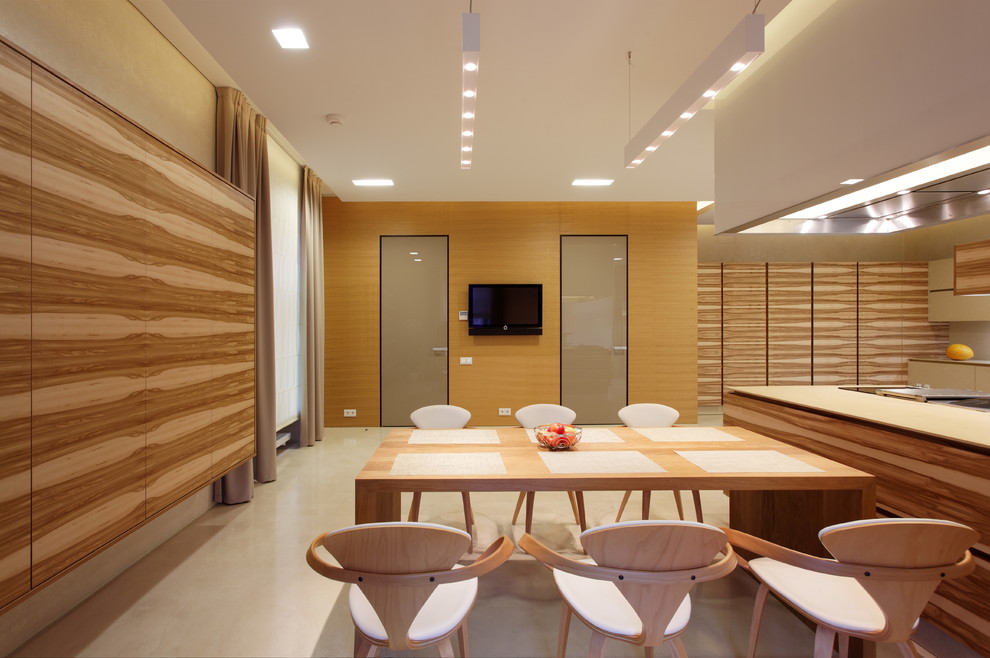 Aménagement d'une salle à manger ouverte sur la cuisine contemporaine avec un mur beige et sol en béton ciré.