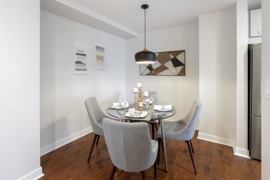 Cette photo montre une petite salle à manger ouverte sur le salon rétro avec un mur blanc, un sol en bois brun et un sol marron.