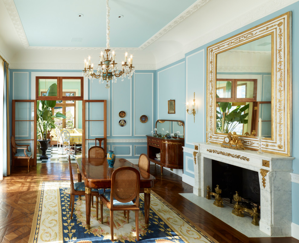 Immagine di una sala da pranzo vittoriana con pareti blu, parquet scuro, camino classico, cornice del camino in intonaco e pavimento marrone