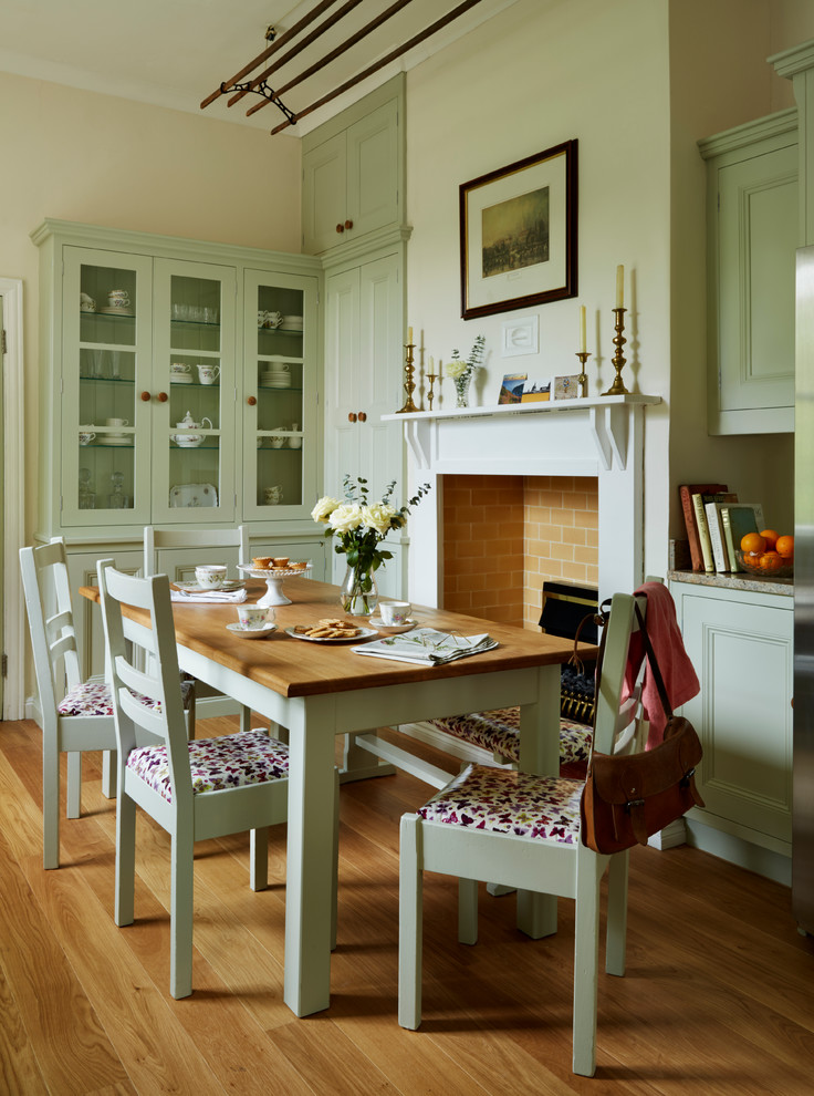Mittelgroße Klassische Wohnküche mit beiger Wandfarbe, braunem Holzboden, Kamin und Kaminumrandung aus Holz in Sonstige