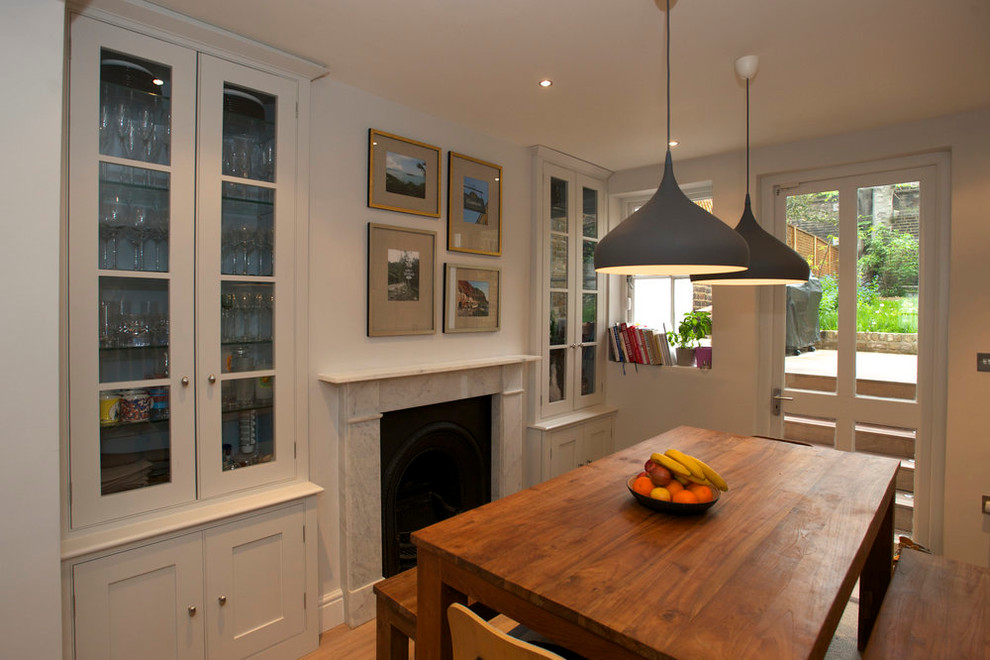 This is an example of a contemporary dining room in London with grey walls, medium hardwood flooring, a standard fireplace and a stone fireplace surround.