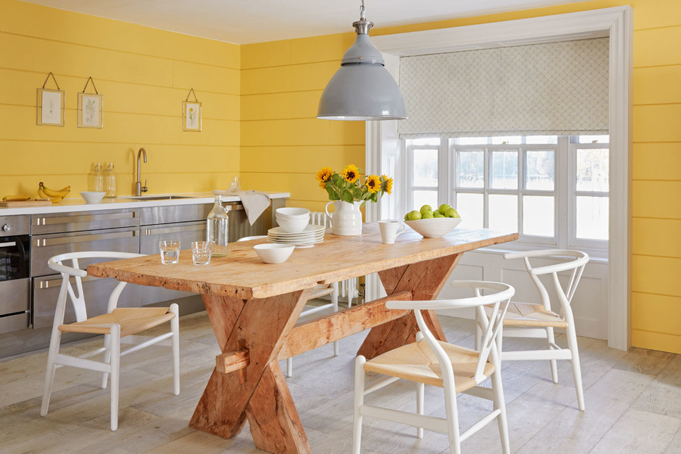Esempio di una sala da pranzo aperta verso la cucina country di medie dimensioni con pareti gialle, pavimento grigio e parquet chiaro