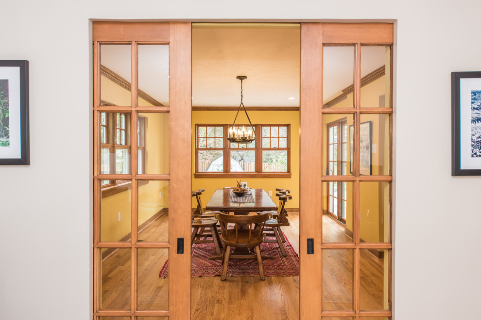 Esempio di una sala da pranzo aperta verso la cucina american style di medie dimensioni con pareti gialle, parquet chiaro e pavimento marrone