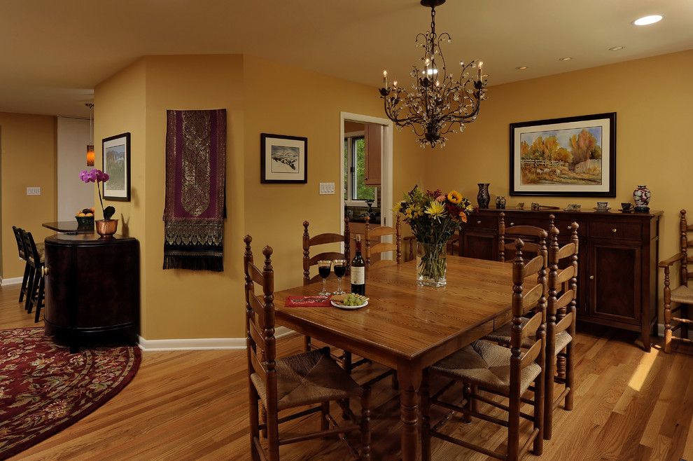 На фото: столовая в классическом стиле с паркетным полом среднего тона и желтыми стенами