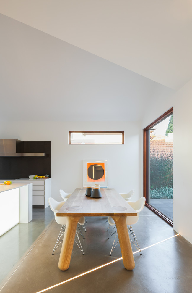 Immagine di una sala da pranzo aperta verso la cucina design con pareti bianche