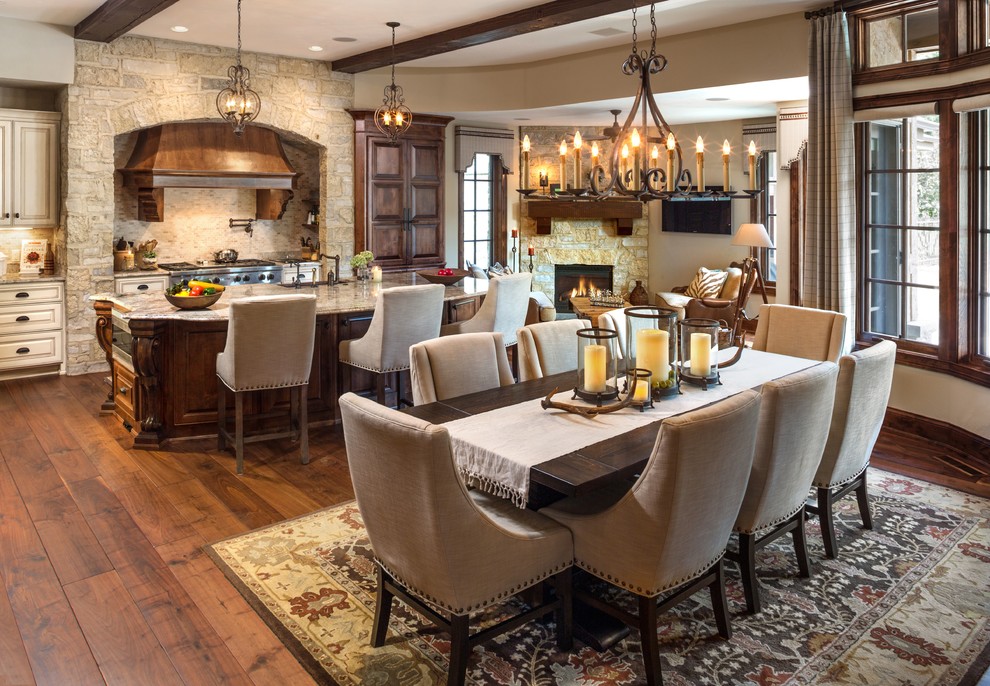Large traditional kitchen/dining room in Milwaukee with dark hardwood flooring, a corner fireplace, a stone fireplace surround and feature lighting.