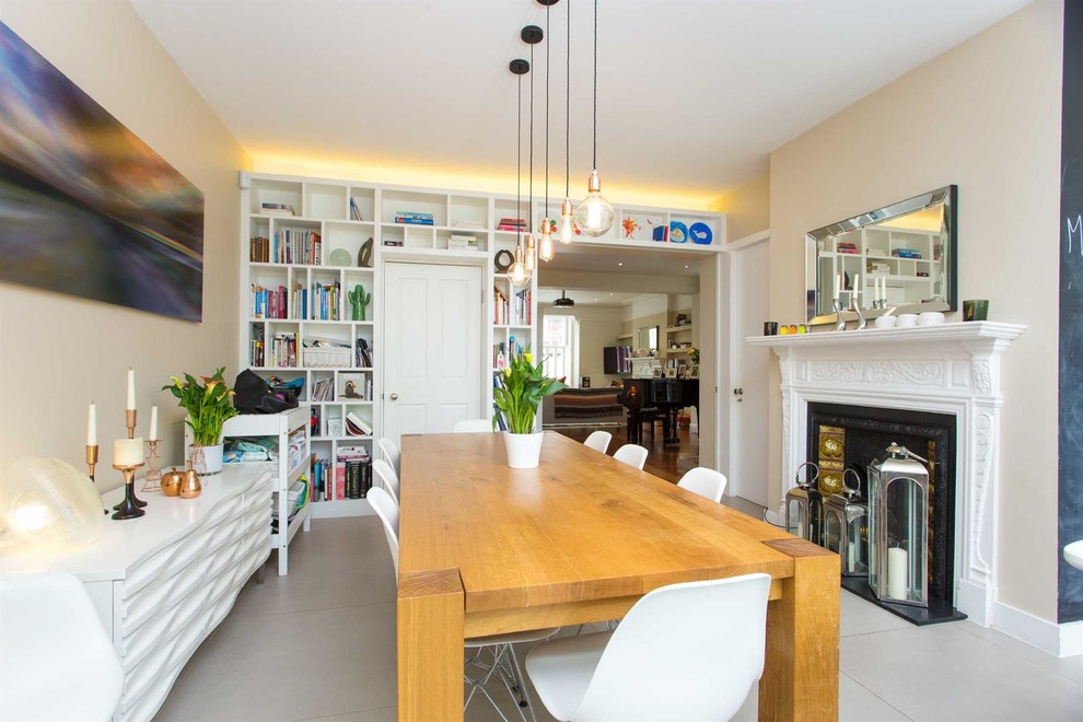 Photo of a large contemporary dining room in London with beige walls, grey floors and a standard fireplace.