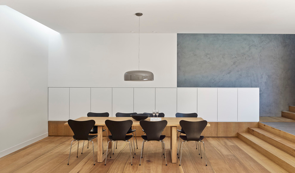 Imagen de comedor actual grande abierto sin chimenea con paredes blancas y suelo de madera en tonos medios
