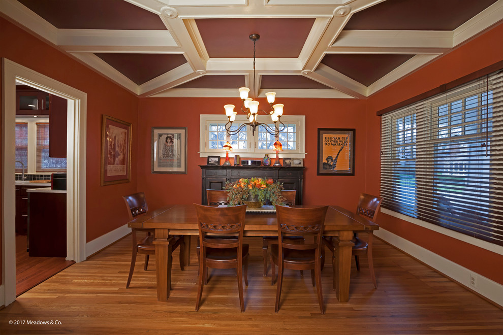 Cette image montre une salle à manger craftsman fermée et de taille moyenne avec un mur orange, parquet clair, aucune cheminée, un sol marron et un plafond à caissons.