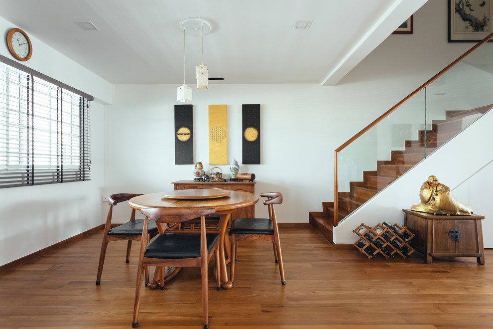 Immagine di una sala da pranzo aperta verso il soggiorno etnica con pareti bianche, pavimento in legno massello medio e pavimento marrone