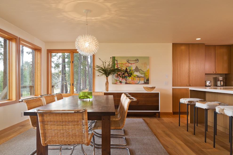 Aménagement d'une salle à manger ouverte sur la cuisine moderne avec un mur beige et un sol en bois brun.