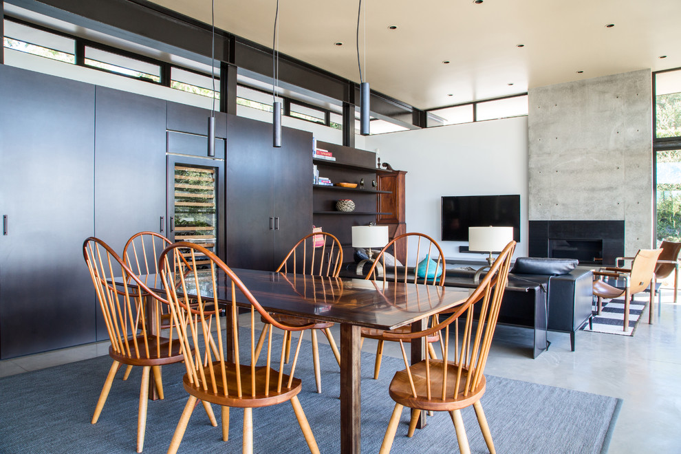 Immagine di una sala da pranzo aperta verso il soggiorno minimal con pavimento in cemento