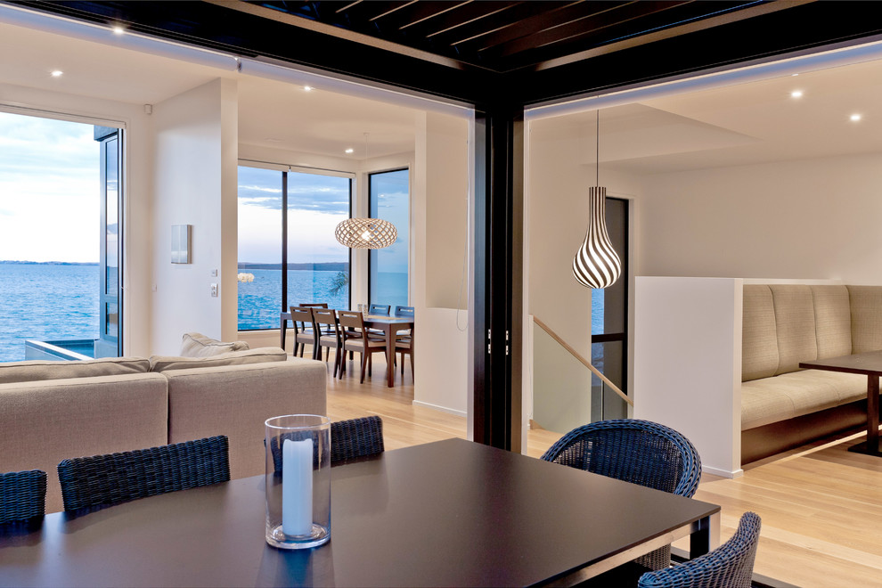 Große Moderne Wohnküche mit weißer Wandfarbe, hellem Holzboden und Kaminumrandung aus Metall in Auckland