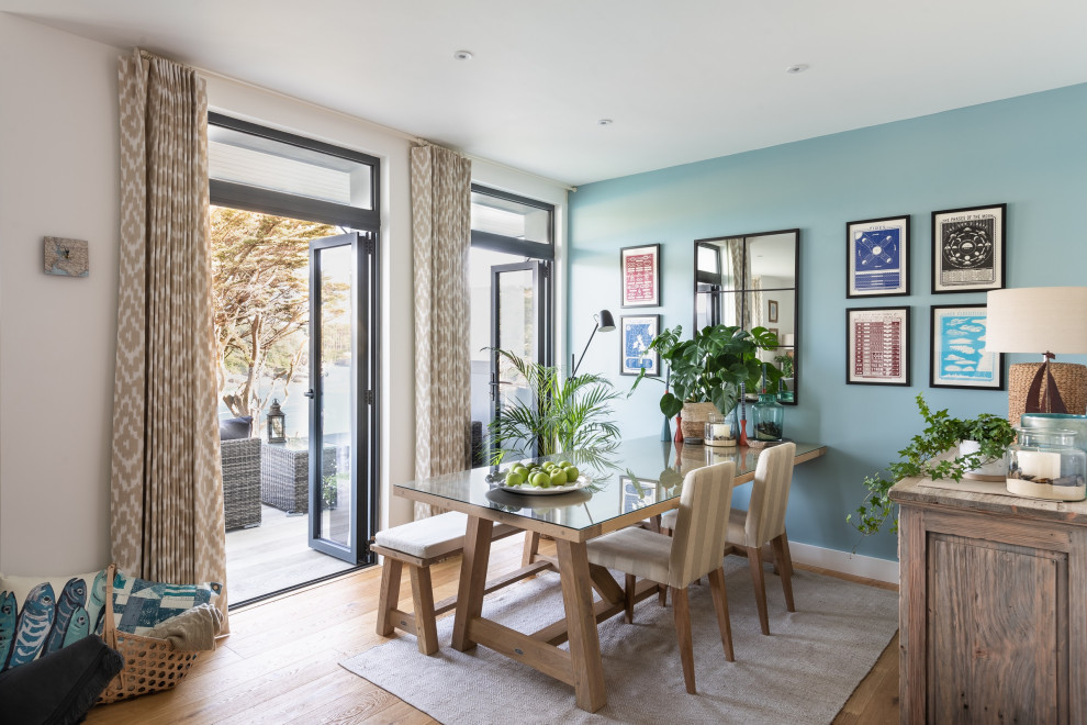На фото: маленькая гостиная-столовая в морском стиле с синими стенами, светлым паркетным полом и коричневым полом для на участке и в саду