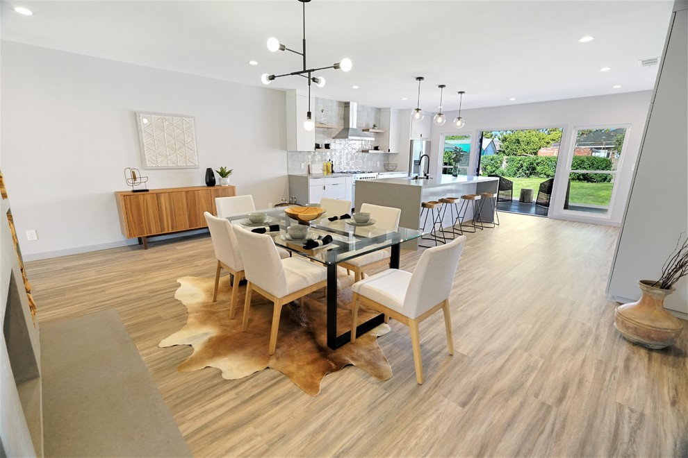 Inspiration pour une salle à manger ouverte sur la cuisine design de taille moyenne avec un mur gris, un sol en vinyl, une cheminée standard, un manteau de cheminée en béton et un sol marron.