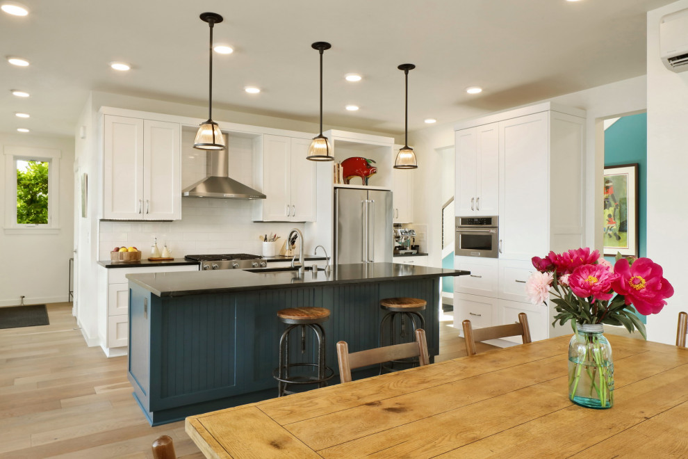 Foto di una sala da pranzo aperta verso la cucina stile marino di medie dimensioni con pareti bianche, pavimento in legno massello medio e pavimento marrone