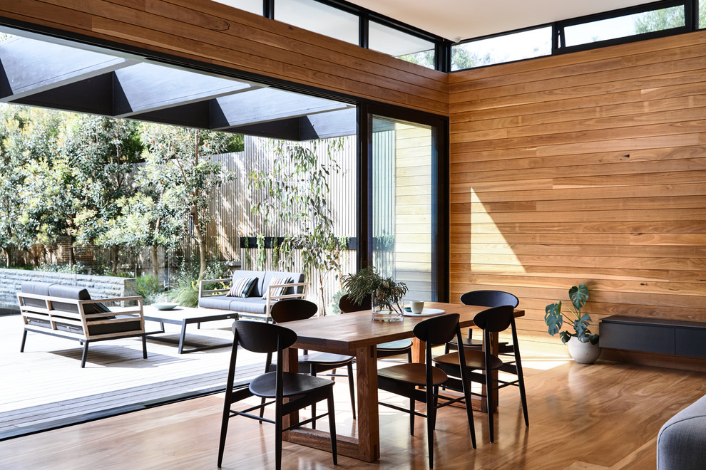 Idées déco pour une salle à manger ouverte sur la cuisine contemporaine de taille moyenne avec un mur marron, un sol en bois brun et un sol orange.