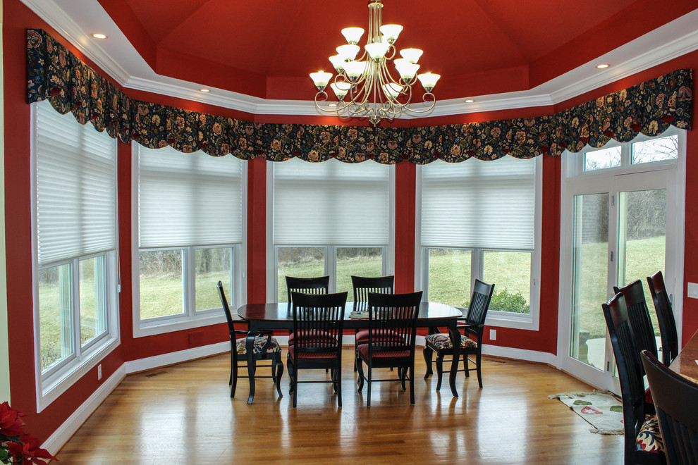 Esempio di una grande sala da pranzo aperta verso la cucina con pareti rosse, pavimento in legno massello medio e nessun camino