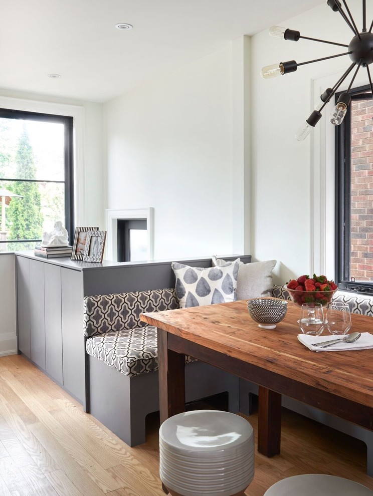 Foto di una sala da pranzo aperta verso la cucina chic di medie dimensioni con pareti bianche, parquet chiaro e pavimento marrone