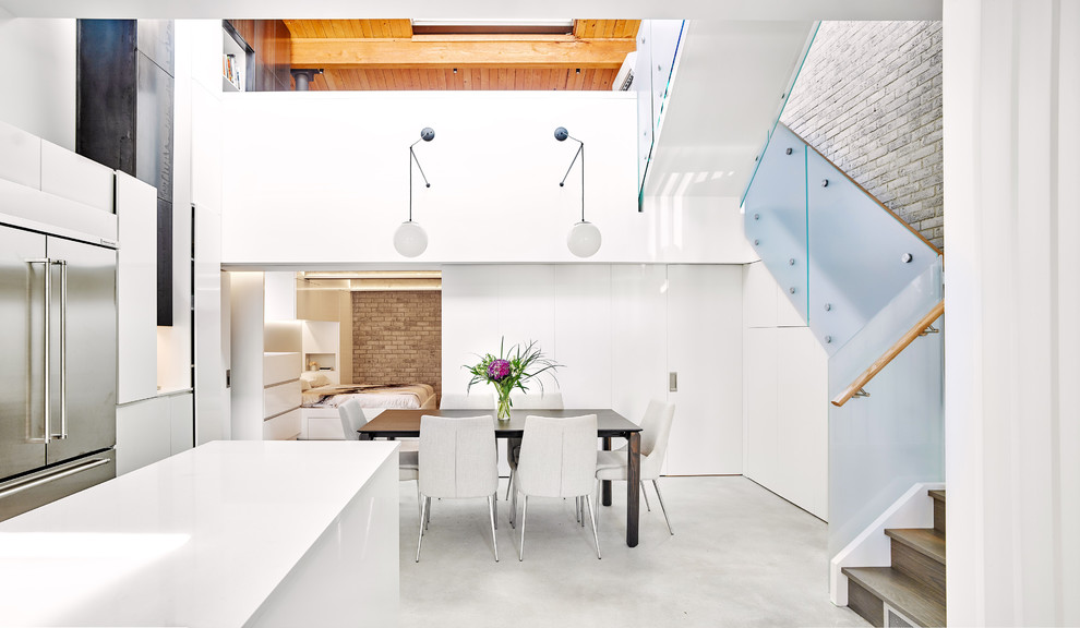 Exemple d'une salle à manger ouverte sur la cuisine tendance de taille moyenne avec un mur blanc et sol en béton ciré.