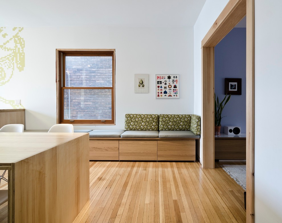 Cette photo montre une salle à manger moderne avec un mur blanc et un sol en bois brun.