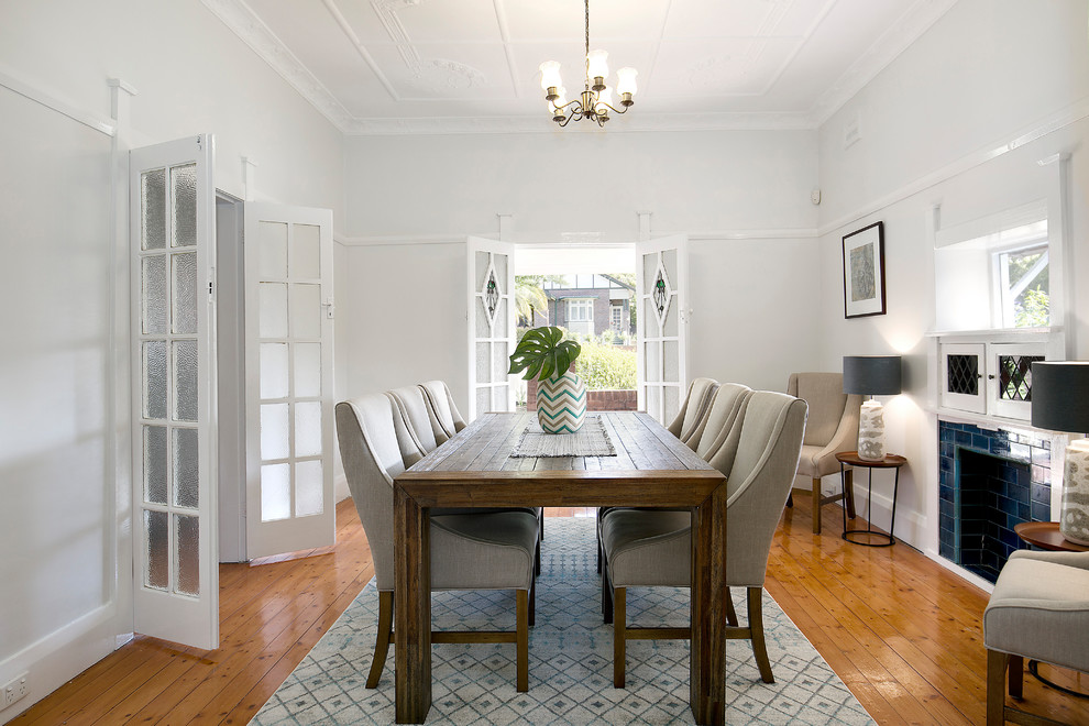 Example of a mid-sized transitional medium tone wood floor and brown floor dining room design in Sydney with white walls