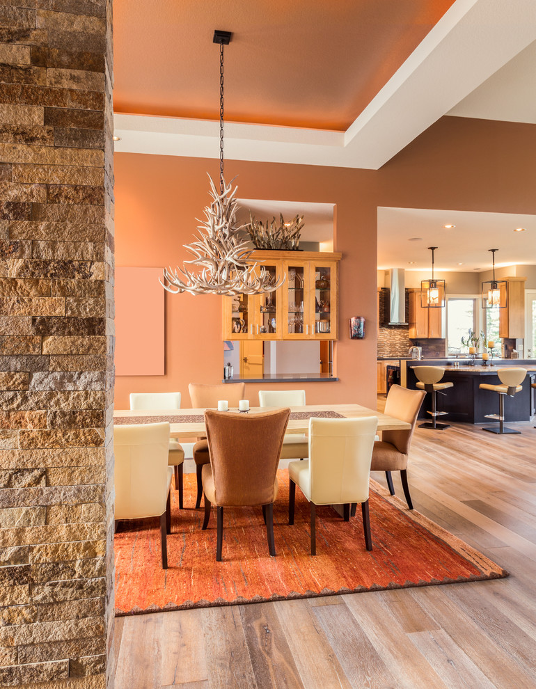 Réalisation d'une salle à manger ouverte sur le salon design avec un mur orange et un sol en bois brun.