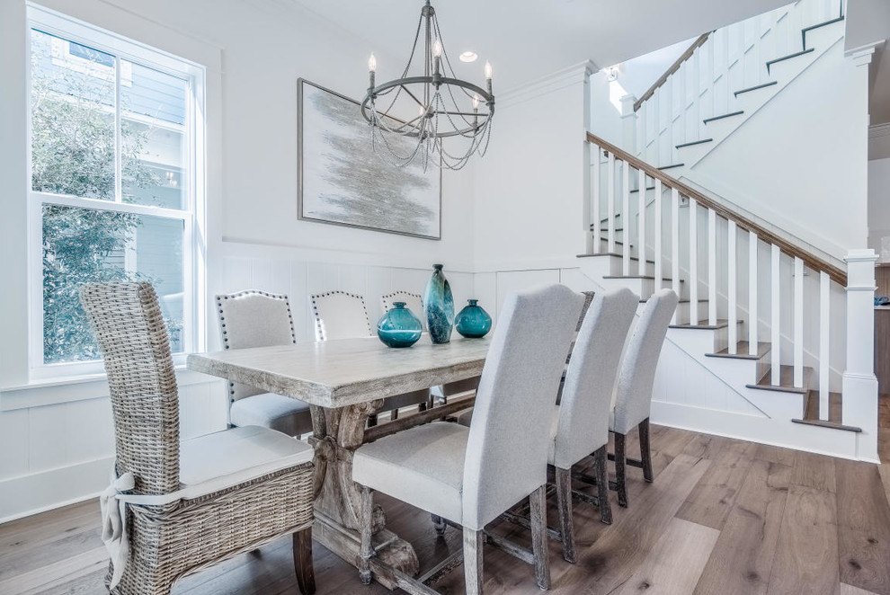 Aménagement d'une salle à manger ouverte sur la cuisine bord de mer de taille moyenne avec un mur blanc, parquet clair, aucune cheminée et un sol beige.