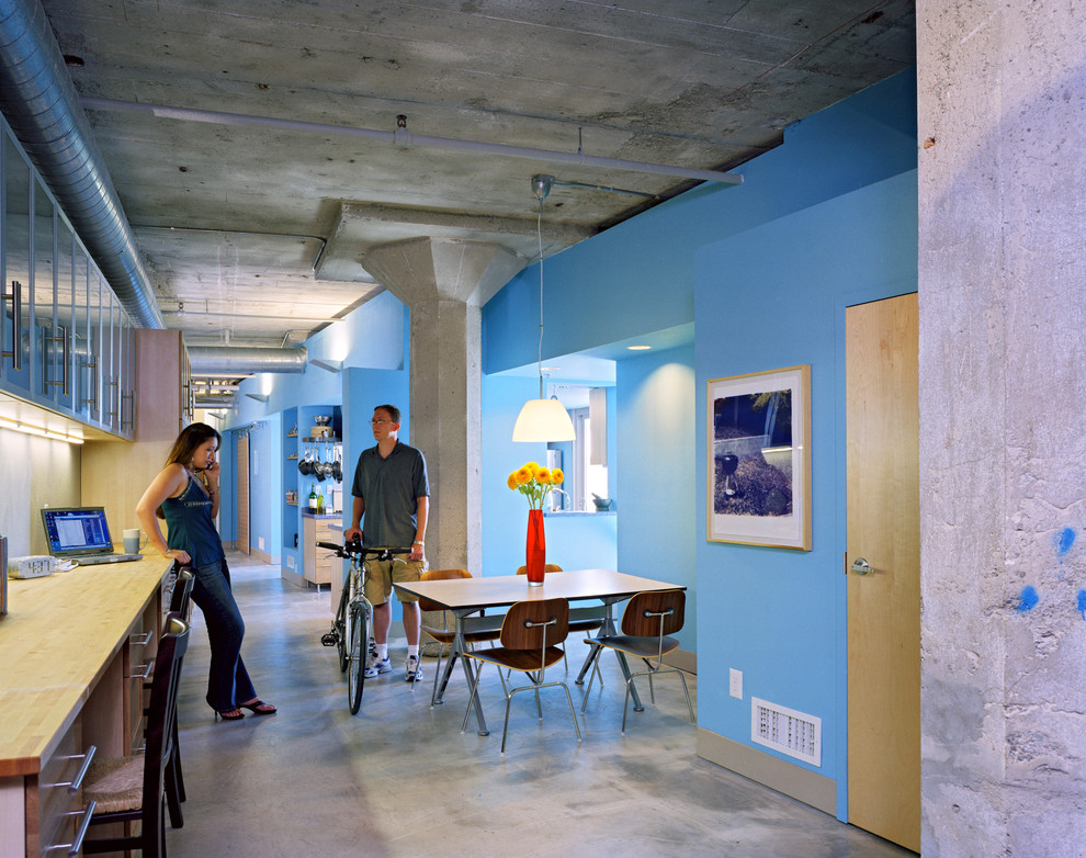 На фото: столовая в стиле лофт с синими стенами и бетонным полом с