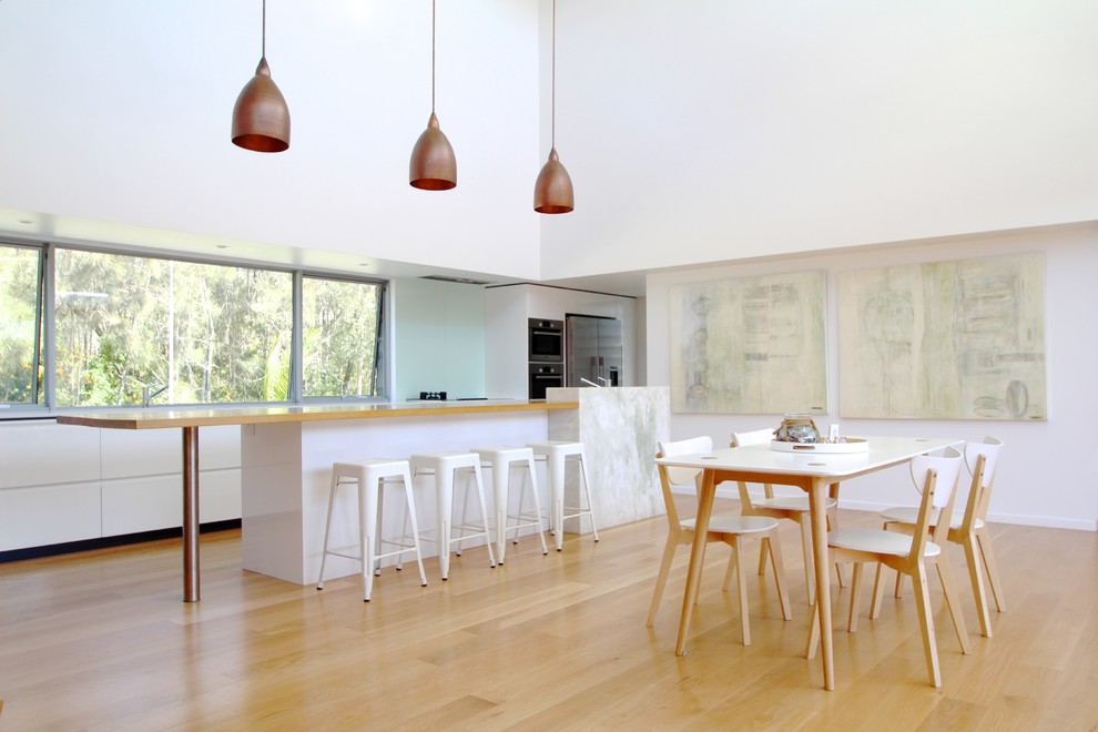 Foto di una grande sala da pranzo aperta verso il soggiorno design con pareti bianche e parquet chiaro