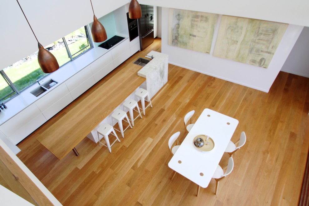 Foto di una grande sala da pranzo aperta verso la cucina contemporanea con pareti bianche e parquet chiaro