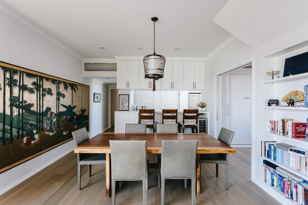 Ispirazione per una sala da pranzo aperta verso la cucina etnica con pareti bianche, pavimento in legno massello medio e pavimento marrone