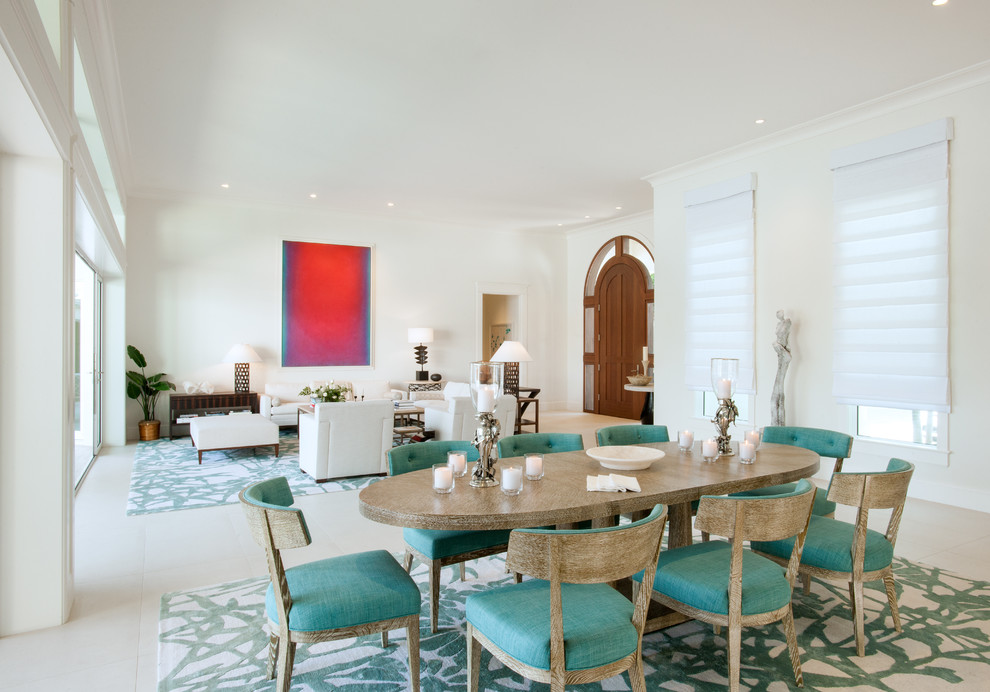 Immagine di una grande sala da pranzo aperta verso il soggiorno mediterranea con pareti bianche e pavimento in travertino
