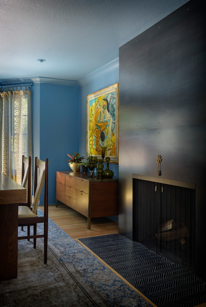 Idee per una sala da pranzo chic di medie dimensioni e chiusa con pareti blu, parquet chiaro, camino classico, cornice del camino in metallo e pavimento marrone