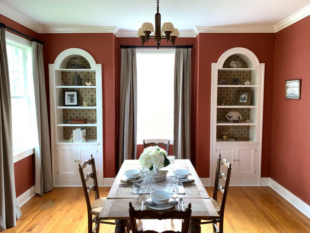 Immagine di una sala da pranzo tradizionale chiusa e di medie dimensioni con pareti rosse, pavimento in legno massello medio, nessun camino, pavimento arancione e carta da parati