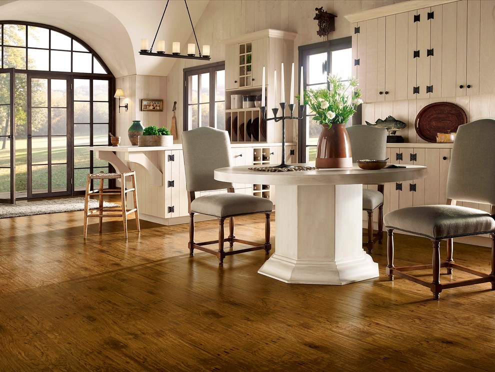 Modelo de comedor de estilo de casa de campo grande sin chimenea con paredes blancas, suelo de madera en tonos medios y suelo marrón