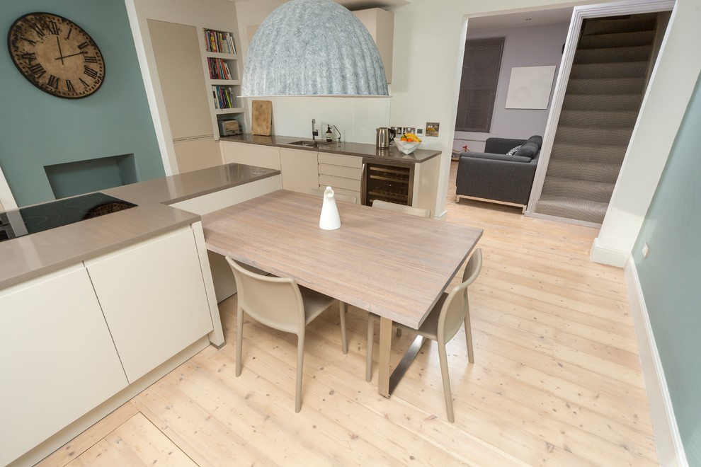 Imagen de comedor contemporáneo de tamaño medio abierto sin chimenea con paredes azules, suelo de madera clara y suelo beige
